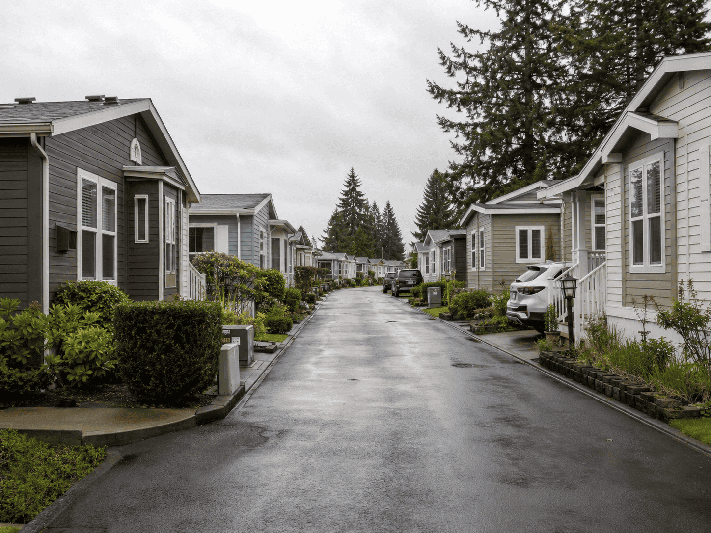 A well-kept manufactured home community with homes on both sides of a narrow paved road